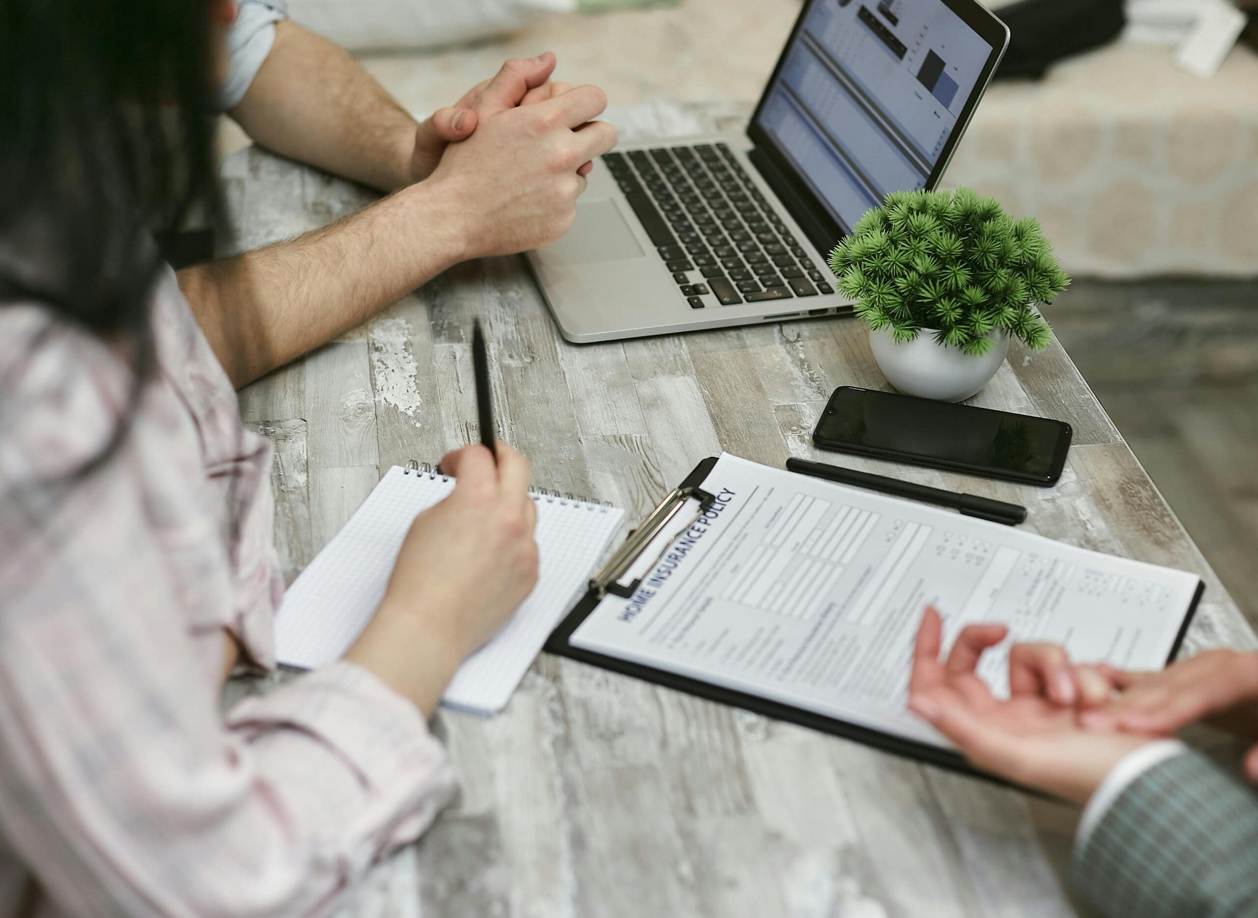 A couple signing a policy for home insurance, working with an independent insurance agency in Tucson.